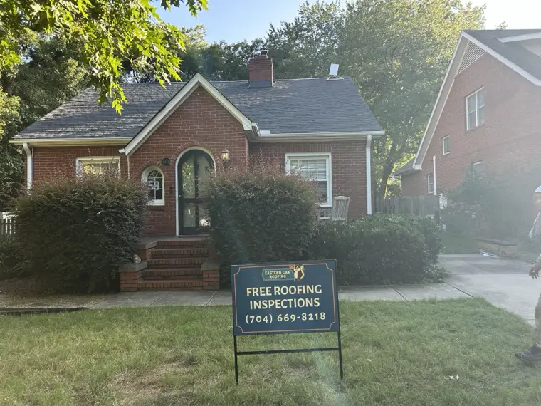 New architectural shingle roof on a brick bungalow with an Eastern Oak Roofing sign out front